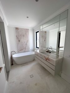 Contemporary bathroom renovation in Rose Bay with freestanding tub, full-height marble wall, custom marble vanity, and brushed bronze tapware.