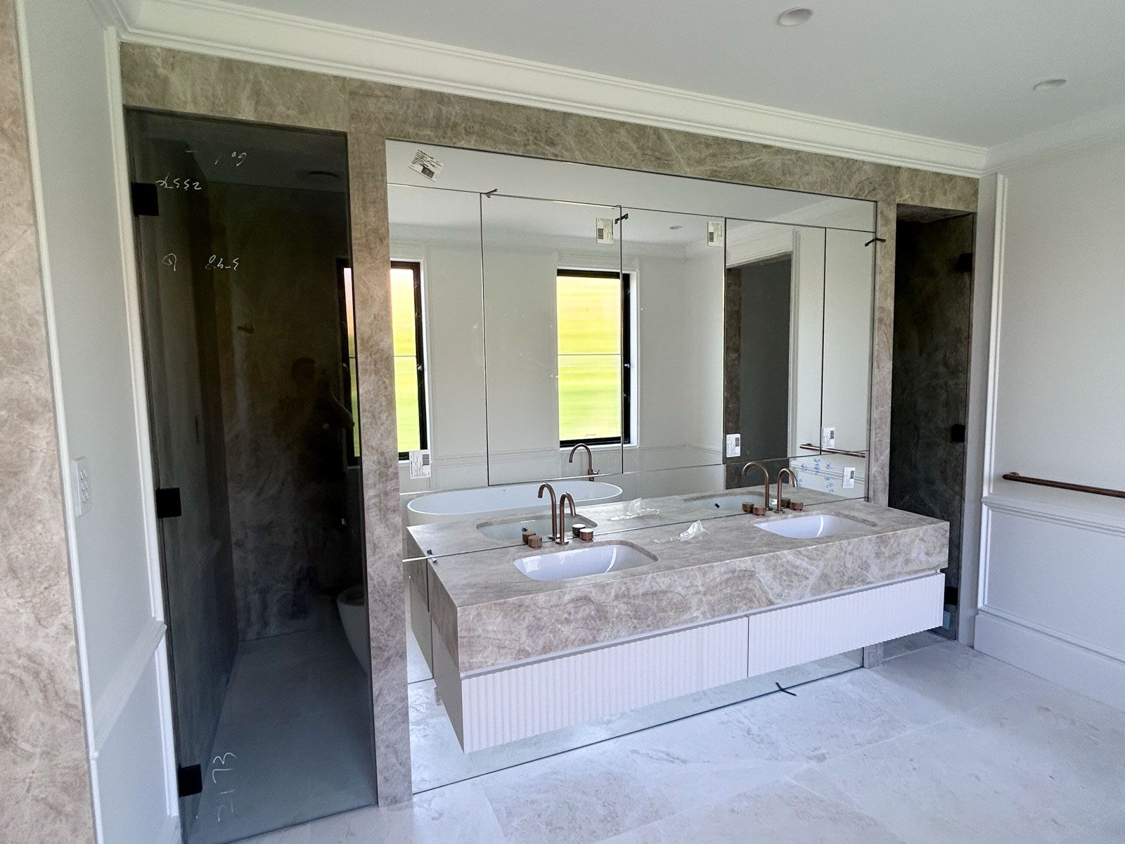 Contemporary bathroom renovation in Rose Bay with freestanding tub, full-height marble wall, custom marble vanity, and brushed bronze tapware.