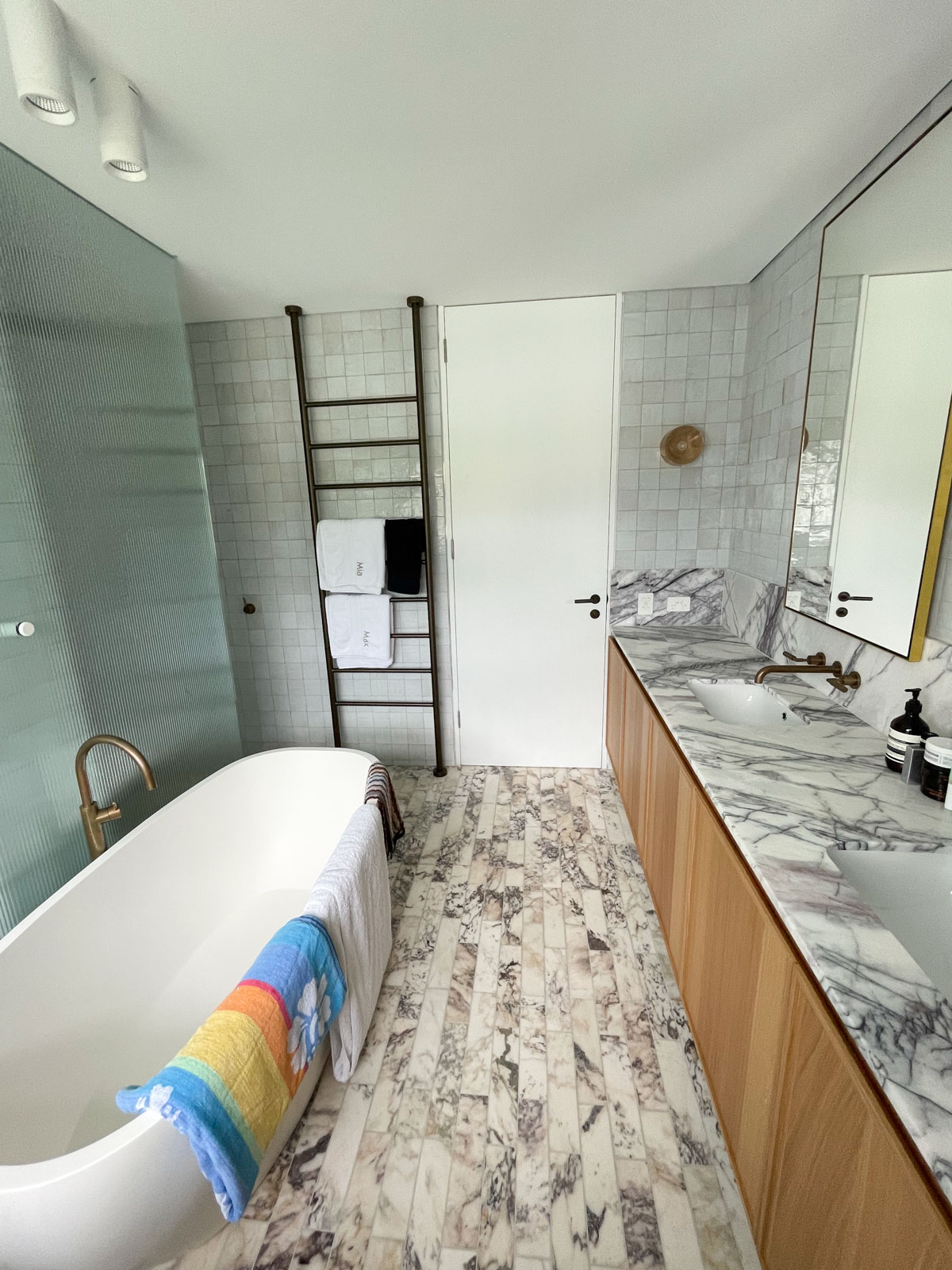 Gleeson Build Construction Modern kitchen renovation in Rose Bay with large natural marble island, custom cabinetry, dark timber parquet flooring, and arched glass doors.