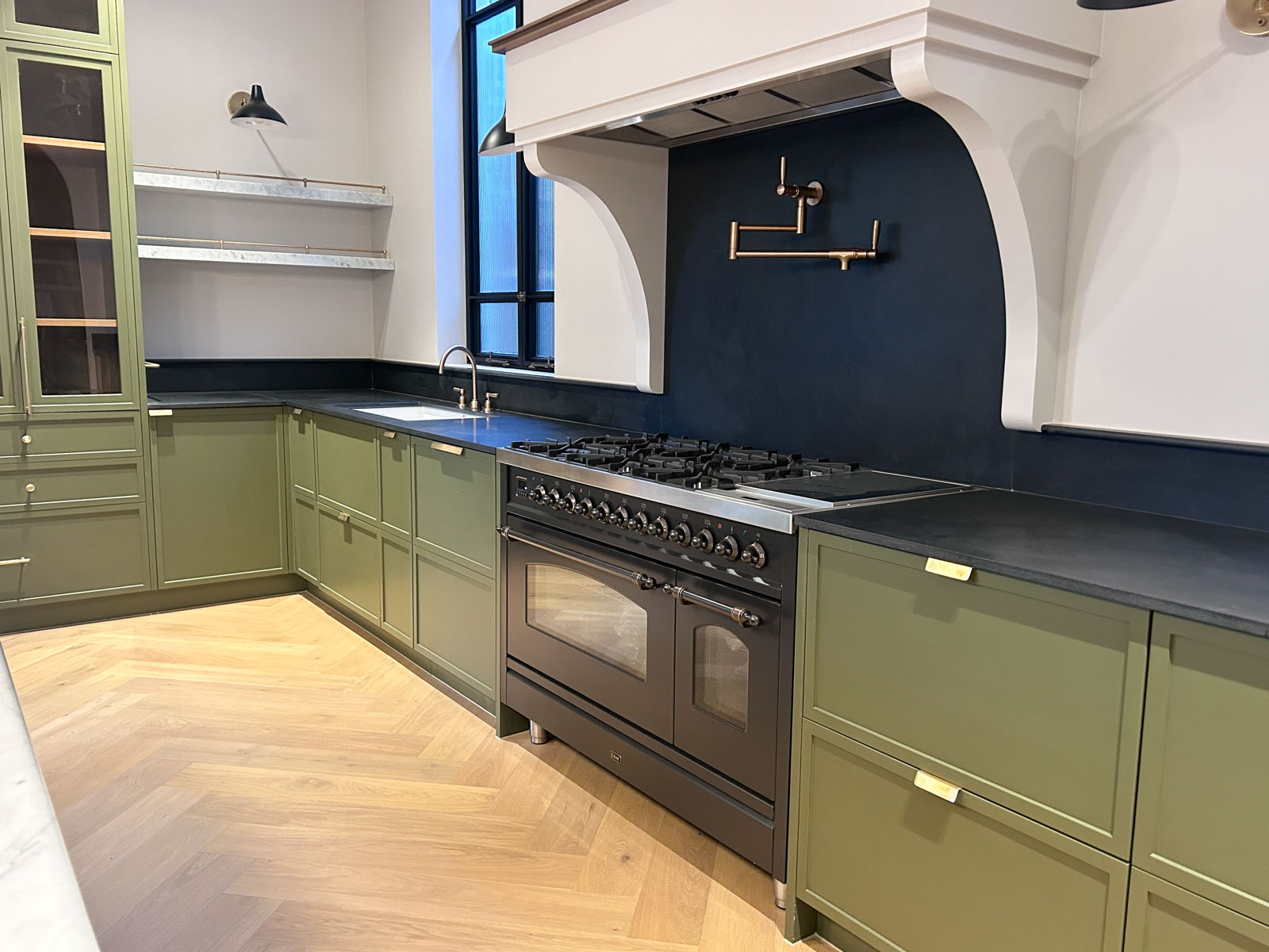 Gleeson Build Construction Modern kitchen renovation in Rose Bay with large natural marble island, custom cabinetry, dark timber parquet flooring, and arched glass doors.